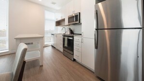 A modern kitchen with stainless steel appliances, white cabinetry, and a wooden floor. - Landing | Modern 2BD, Courtyard, Gym (Alexandria)