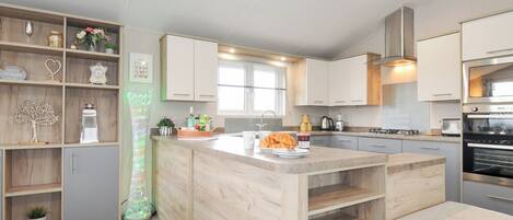 A modern kitchen with wooden cabinetry, a central island, and built-in appliances.