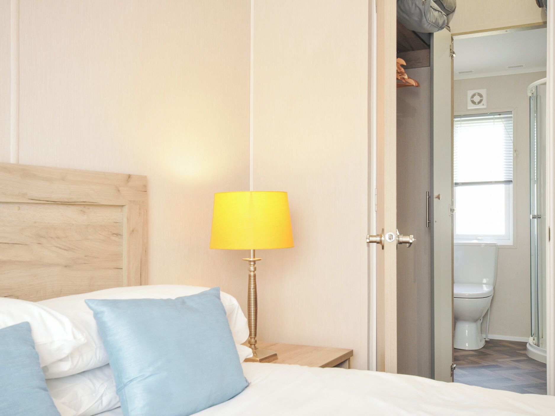 A bedroom with a bed, a nightstand, a lamp, and a door leading to a bathroom.