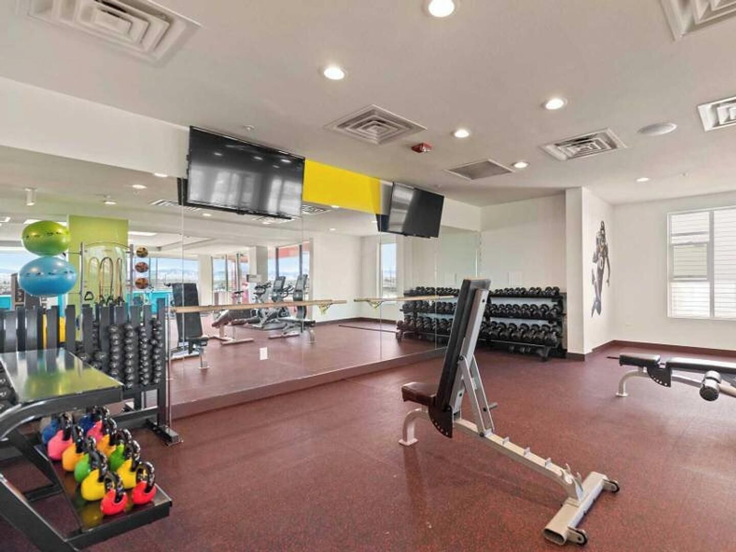 Une salle de sport équipée de matériel d’exercice, d’un téléviseur et d’une grande fenêtre.