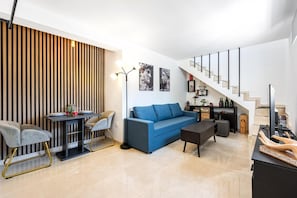 Ein modernes Wohnzimmer mit einer Couch, Sesseln, einem Esstisch und einer Treppe.