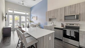 Et moderne køkken med en central ø, rustfrie hårde hvidevarer og udsigt udad.