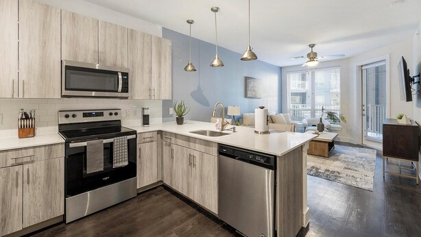 A modern kitchen with stainless steel appliances, a central island with a sink, and pendant lighting. - Landing | Modern 1BD in Bricktown (Fort Worth)