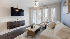 Un salon moderne doté d’un téléviseur à écran plat, d’un ventilateur de plafond, d’un canapé et d’une table basse.