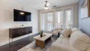 A modern living room with a flat-screen TV, a ceiling fan, a sofa, and a coffee table.