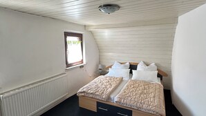 Huone, jossa on sänky, ikkuna ja patteri.