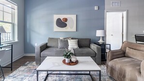 Una sala de estar con un sofá gris, una mesa de centro blanca y una pared azul como detalle.