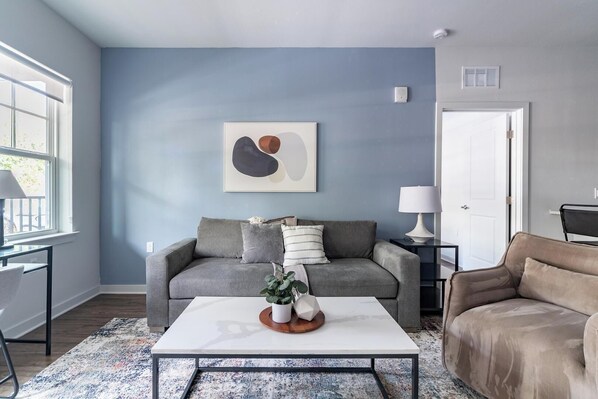 A living room with a grey sofa, a white coffee table, and a blue accent wall. - Landing | Spectacular 2BD, Yoga Studio (Kissimmee)