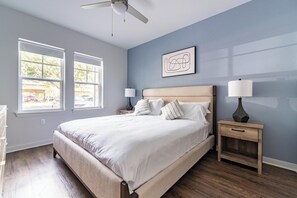 A bedroom with a bed, two bedside tables, a ceiling fan, and two windows. - Landing | Spectacular 2BD, Yoga Studio (Kissimmee)