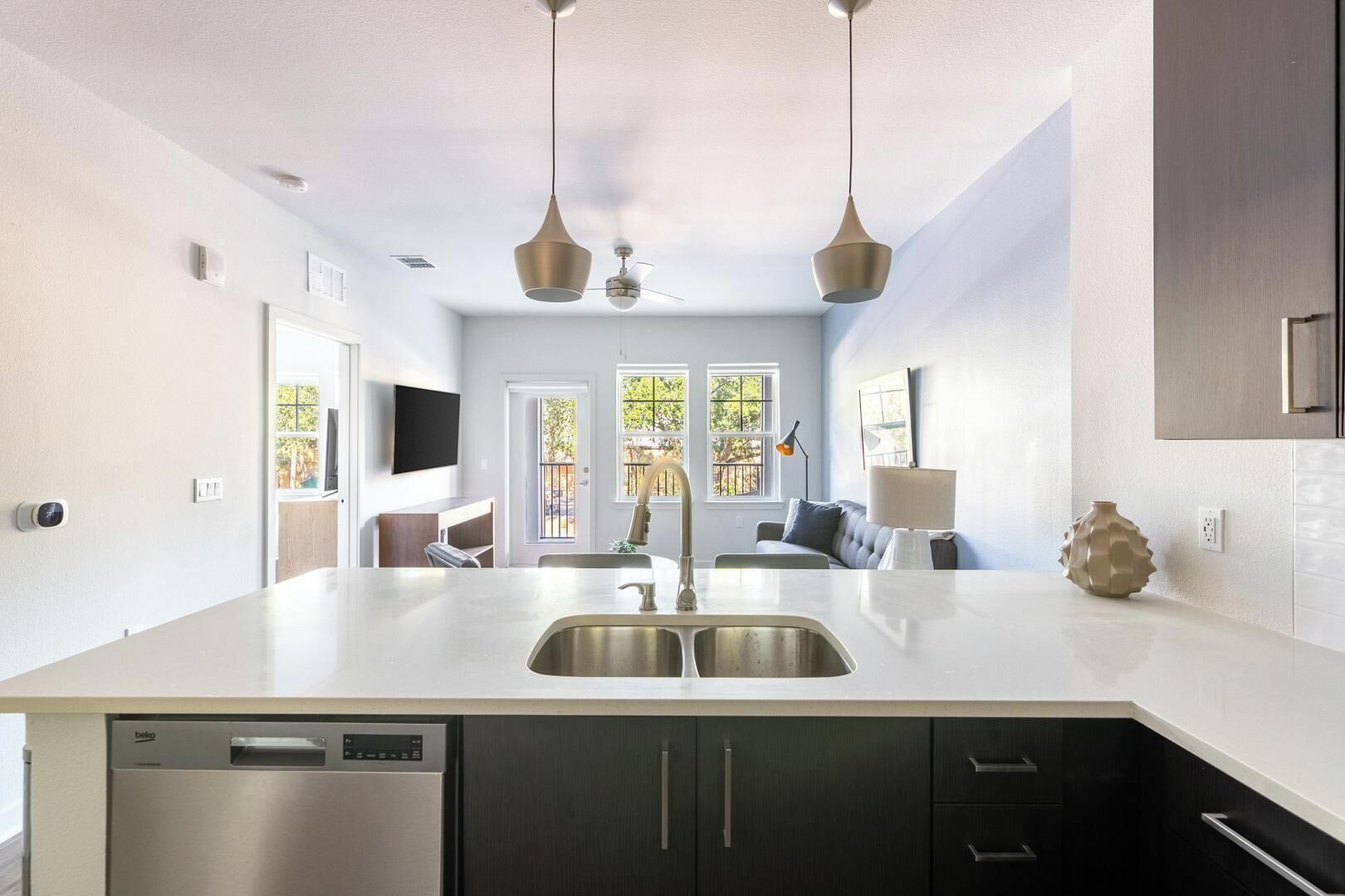 Una cocina moderna con una isla grande, armarios oscuros e iluminación colgante.