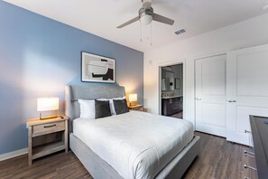 A bedroom with a bed, nightstands, a ceiling fan, a bathroom visible through an open door, and a framed picture on the wall. - Landing | Amazing 1BD, Yoga Studio (Kissimmee)