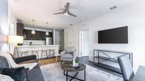 Un salon moderne avec un canapé, des fauteuils, une table basse et un téléviseur.