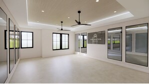 A spacious, modern interior with large windows, ceiling fans, and a sign for Arlington Properties. - Landing | Amazing 1BD, Gym, Pool (Orange Beach)