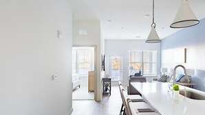 A modern kitchen with a central island, pendant lighting, and a view to the dining area. - Landing | Amazing 1BD, Pool, Yoga Studio (Orange Beach)