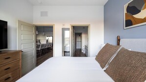 A bedroom with a large bed, a TV, a dresser, and a painting on the wall. - Landing | Amazing 1BD, Pool, Yoga Studio (Orange Beach)