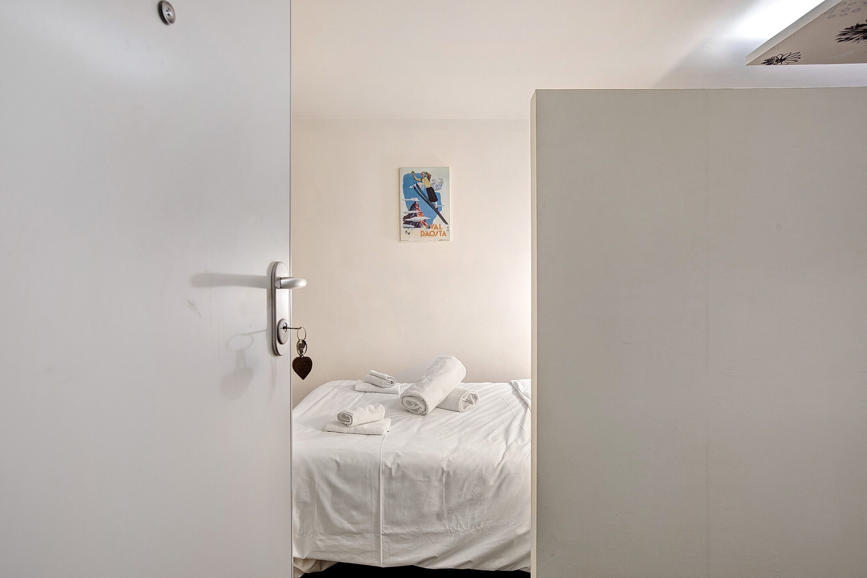 Ein Hotelzimmer mit einem Bett, einer Tür und einer Wand mit einem Poster.