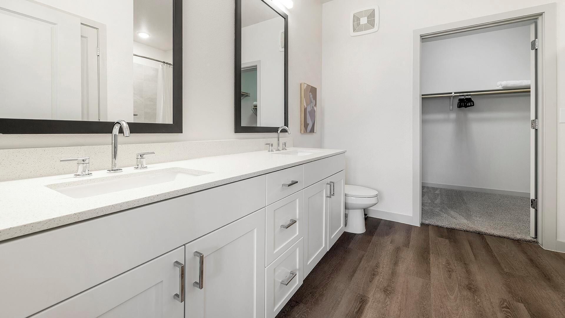 Un bany modern amb un doble lavabo, un vàter i una dutxa aïllada.