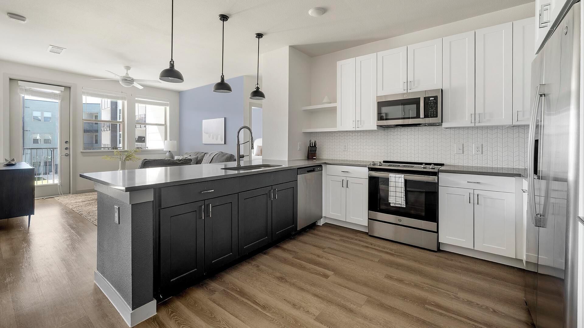 A modern kitchen with a central island, stainless steel appliances, and white cabinetry.