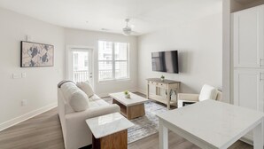 Una sala moderna con sofá, mesa de centro, televisor y zona de comedor.