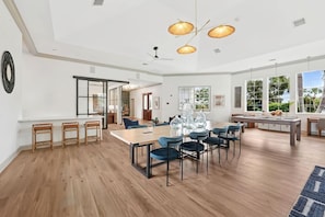 A spacious dining area with a long table, multiple chairs, and a ceiling light fixture. - Landing | Chic 2BD, Gym, Clubhouse (Fruitville)