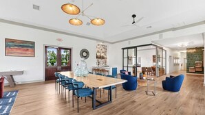 Ein geräumiges Zimmer mit Holzboden, einem großen Tisch mit Stühlen und einem Deckenventilator.