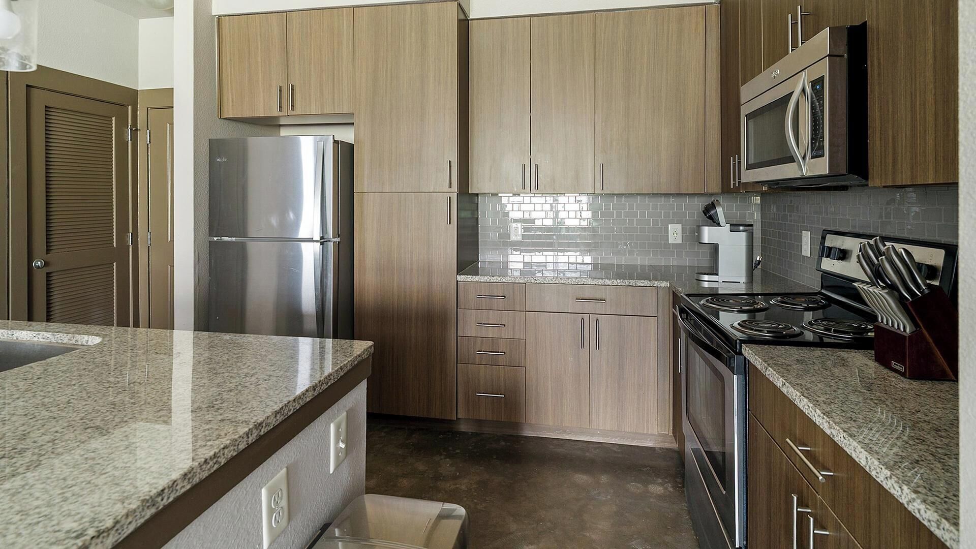 A modern kitchen with wooden cabinets, stainless steel appliances, and a granite countertop.