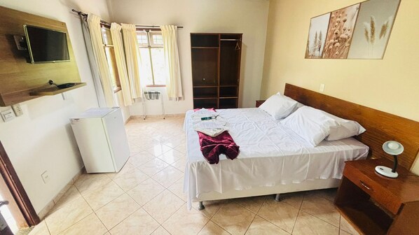A bedroom with a bed, bedside table, and a wardrobe. - Chalés Casa Rosa (Alto Paraíso de Goiás)