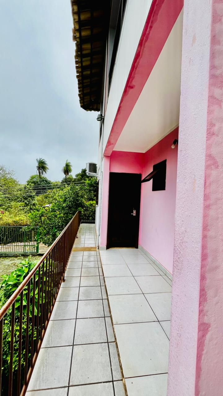 A corridor with tiled flooring, a pink wall, and a black door.