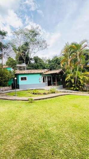 A single-story house with a tiled roof, a small porch, and a well-maintained lawn. - Chalés Casa Rosa (Alto Paraíso de Goiás)