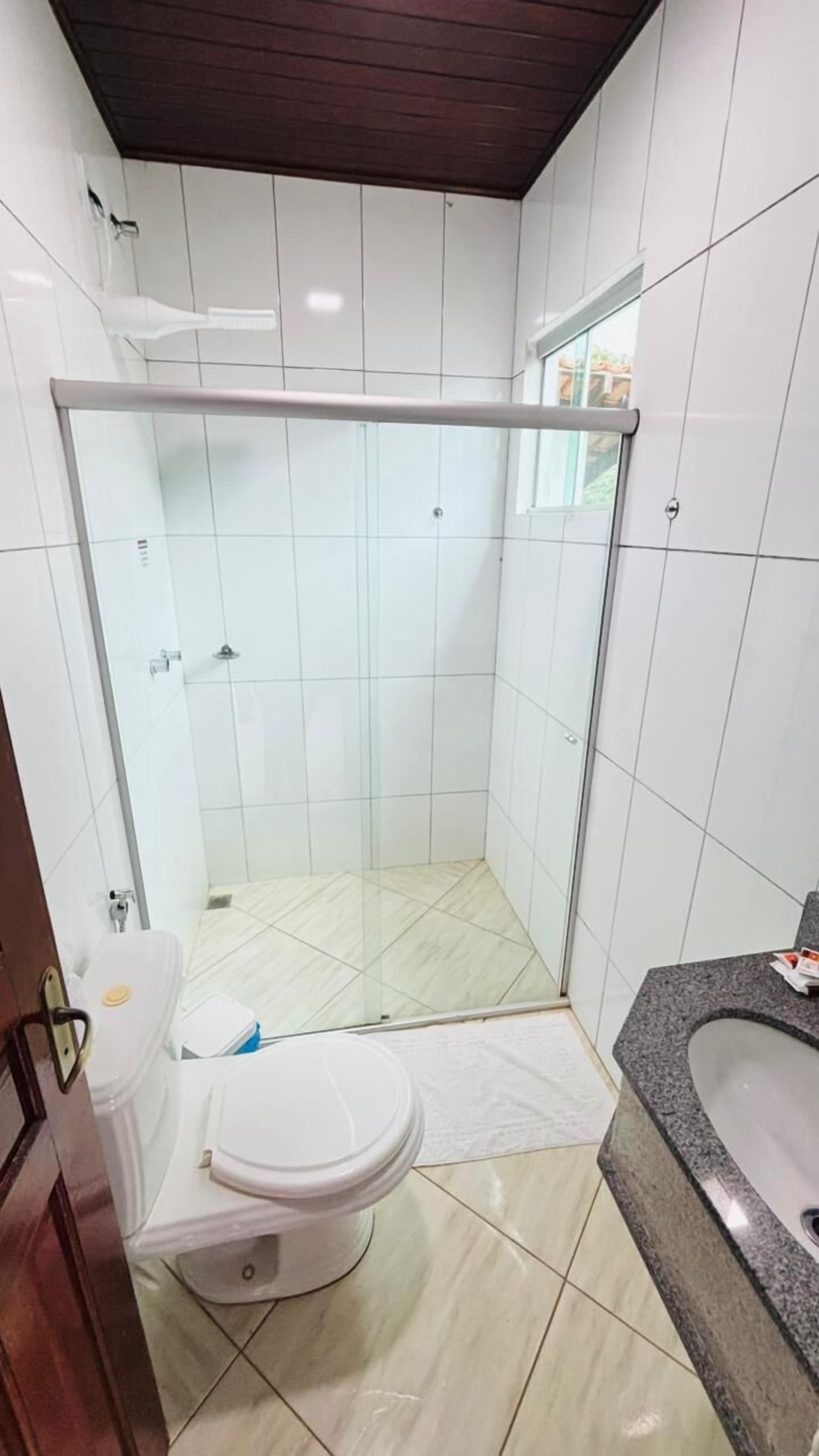 A bathroom with a glass-enclosed shower, a toilet, and a sink.
