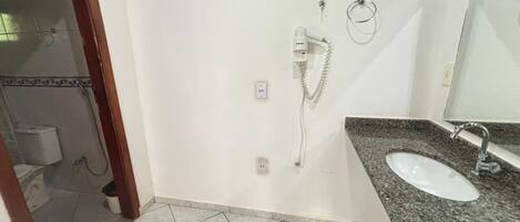 A bathroom with a white sink, a mirror, and a shower head mounted on the wall.