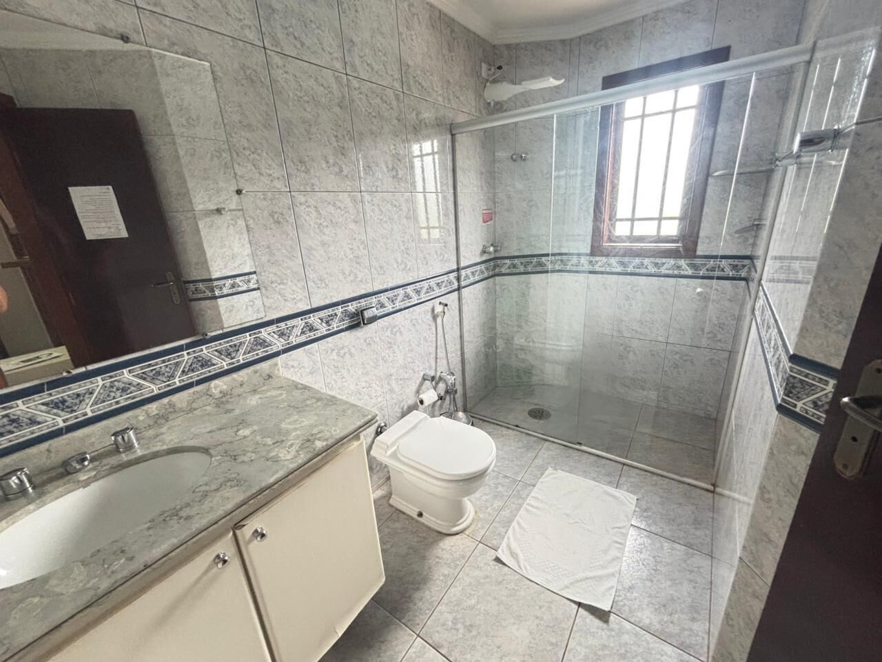 A bathroom with a marble sink, toilet, and a glass-enclosed shower.