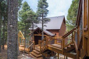 A wooden cabin with a metal roof, surrounded by trees. - RidgeWalk Treehouse - Epic Views at 9200' & Decks (Angel Fire)