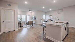 A spacious kitchen with a central island, recessed ceiling lights, and a dining area with a table and chairs. - Landing | Beautiful 2BD, Pool (Tice)