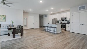 Una cocina moderna con armarios blancos, electrodomésticos de acero inoxidable y una isla central con taburetes de bar.
