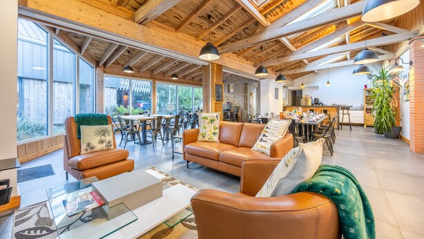 Un interior espacioso con techo alto, sofás de cuero, zona de comedor y ventanas amplias.