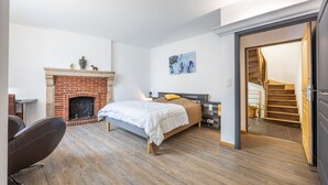 Une chambre avec une cheminée en briques, un lit, un bureau et une chaise.