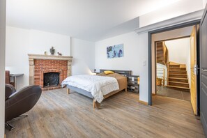 Une chambre avec une cheminée en briques, un lit, un bureau et une chaise.
