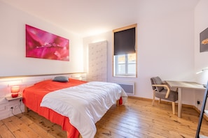 Ein Schlafzimmer mit Bett, Nachttisch, Stuhl und Fenster.