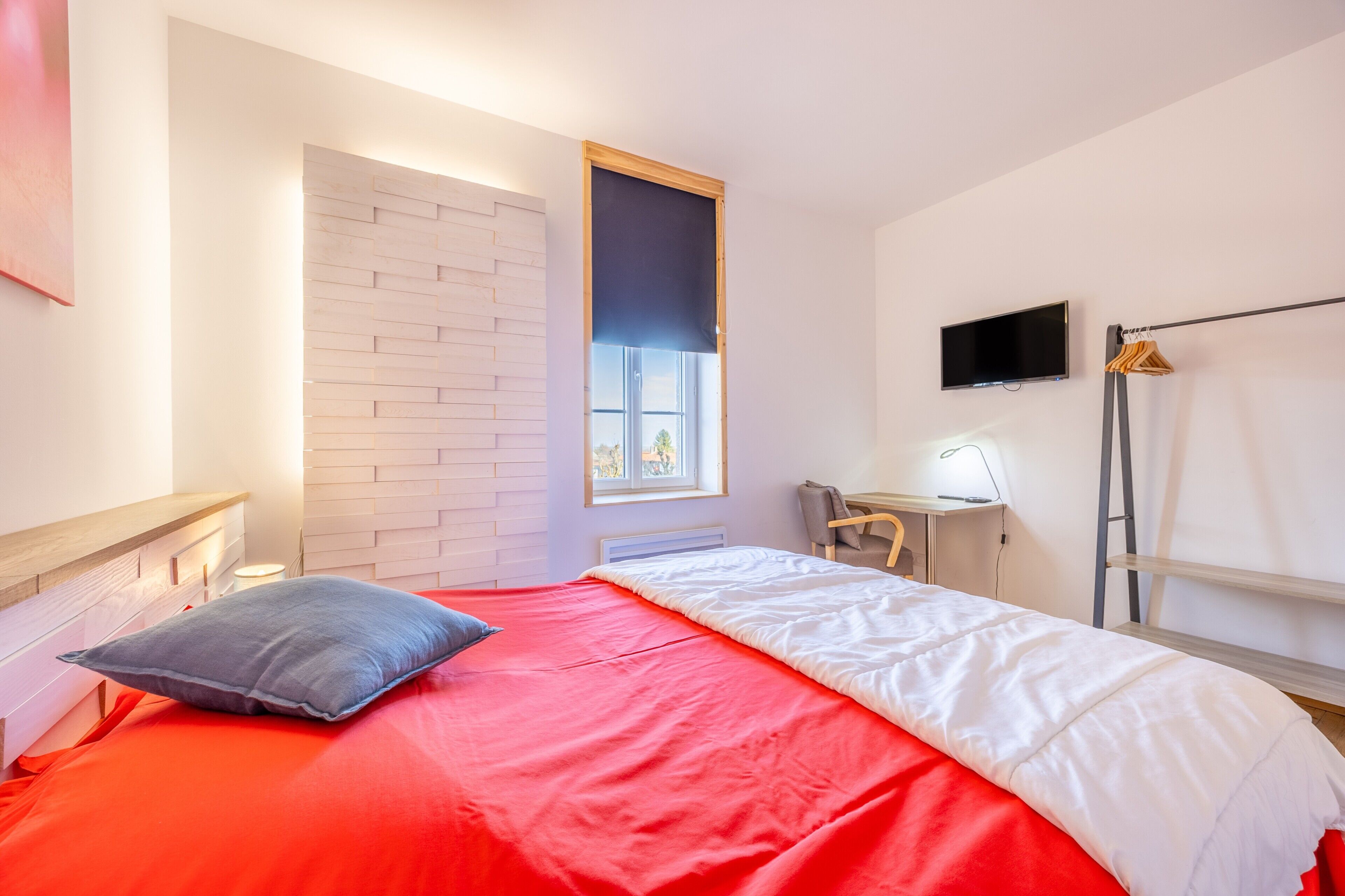 Une chambre à coucher avec un lit, un bureau, une chaise, une télévision et une fenêtre.