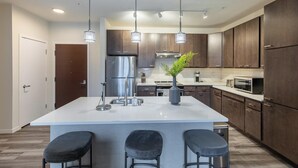 Una cocina moderna con una isla central, electrodomésticos de acero inoxidable y armarios de madera oscura.
