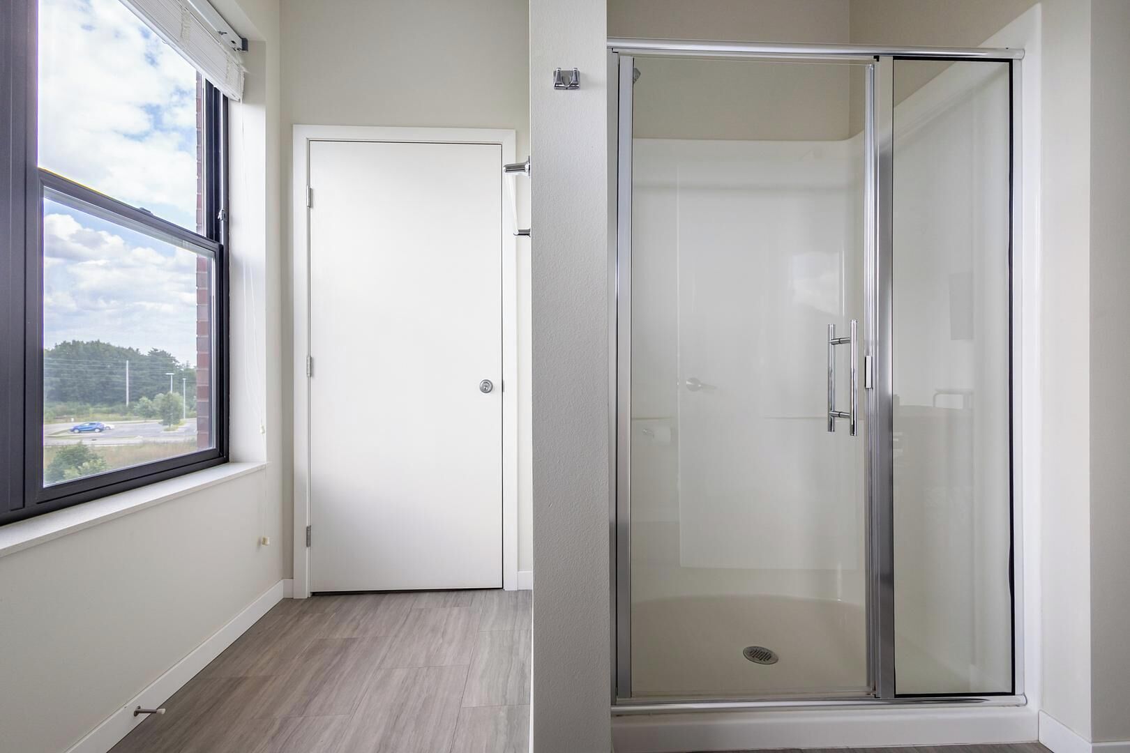 Una habitación con un ventanal grande, una puerta y un área de ducha con paredes de vidrio.
