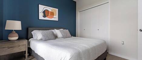 A bedroom with a bed, bedside table, lamp, and a door.
