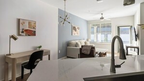Una cocina moderna con una isla central, un comedor con sofá y un espacio de trabajo con escritorio y silla.