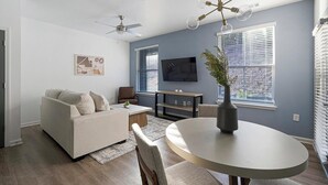 A modern living room with a sofa, coffee table, and a TV mounted on the wall. - Landing | Chic 2BD, Clubhouse, Gym (Bessemer)