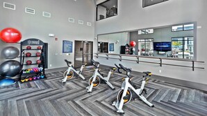 Ein Fitnessraum mit Trainingsrädern, einer Kiste Medizinbälle und einem großen Spiegel, der den Raum widerspiegelt.