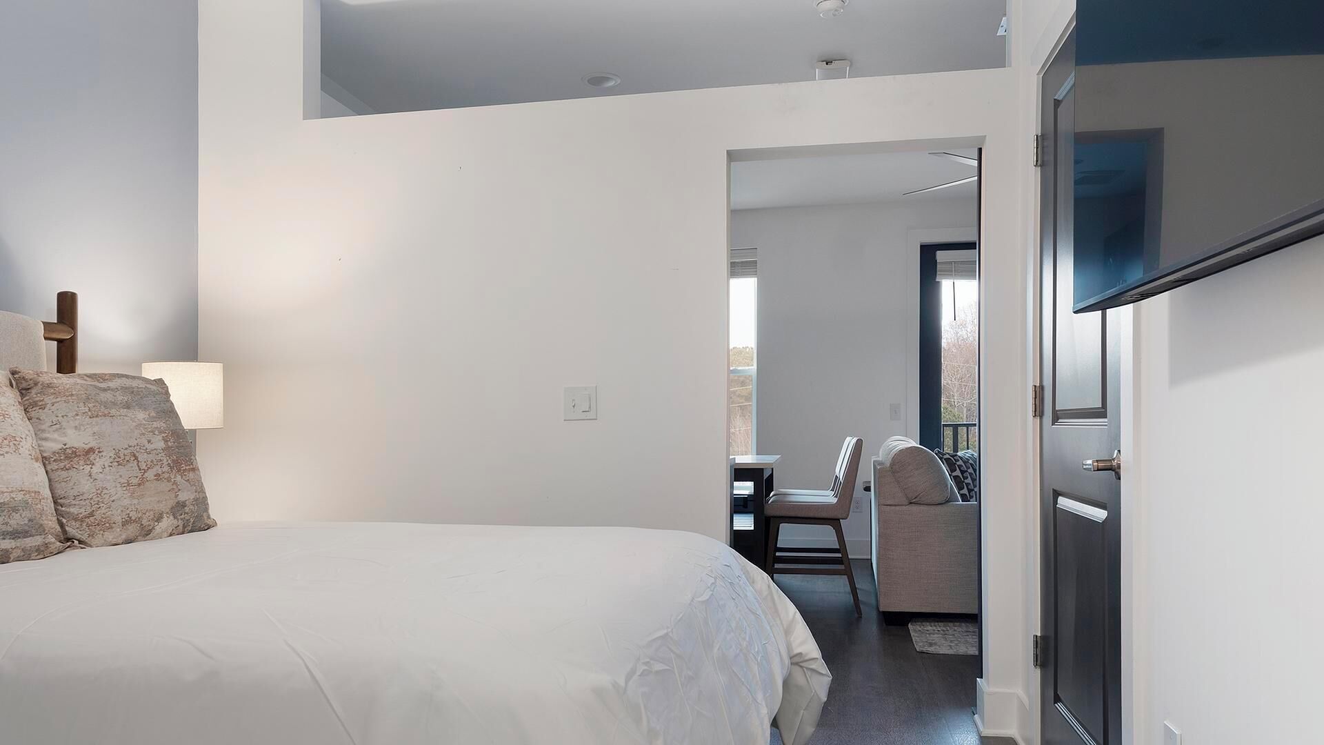 A bedroom with a bed, a desk, and a chair.