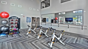 Una palestra con cyclette, un supporto per palle mediche e un grande specchio che riflette l'ambiente.