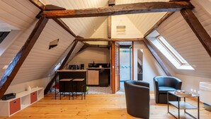 A loft-style room with a wooden floor, a kitchenette, a dining area, and a seating area with a table and chairs. - Studio Tess Apartment with Wi-Fi (Salies-de-Béarn)
