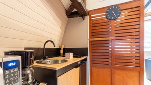 A kitchen with a coffee maker, a sink, and a wooden door with a clock. - Studio Tess Apartment with Wi-Fi (Salies-de-Béarn)